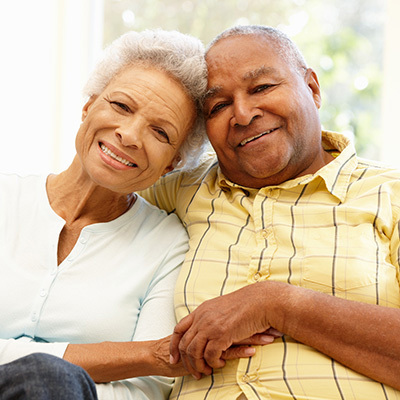 A senior couple on sitting together holding hands.