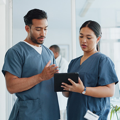 A male and female nurse looking at a clipboard together.