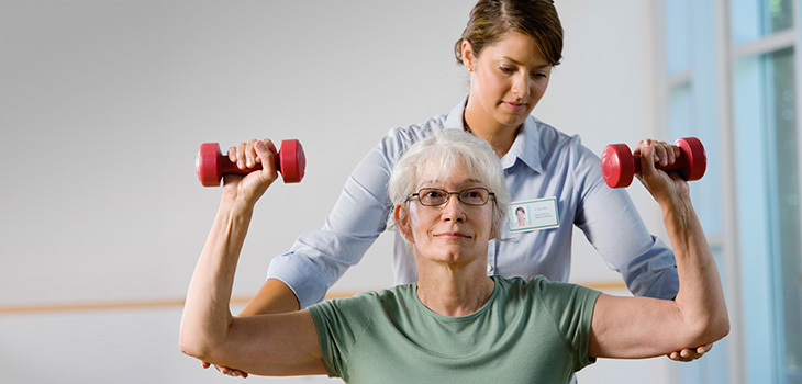 Two women lifting light weights safely together.