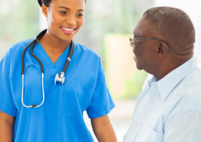 A nurse and a senior smiling at each other.