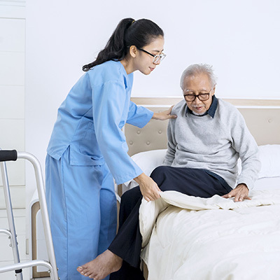 A nurse helping a patient back in bed.