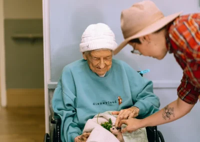 An elderly resident holding a small animal at Glendale Healthcare Center
