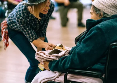 A lady handing a guinea pig to a resident at Glendale Healthcare Center