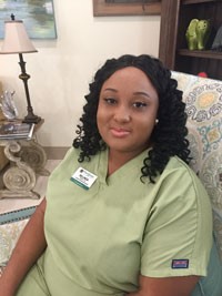 Belinda Tanner sitting and smiling in green scrubs