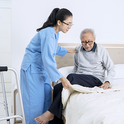 A nurse helping a resident into bed.