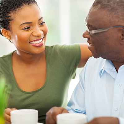 A senior and a young lady drinking coffee together.