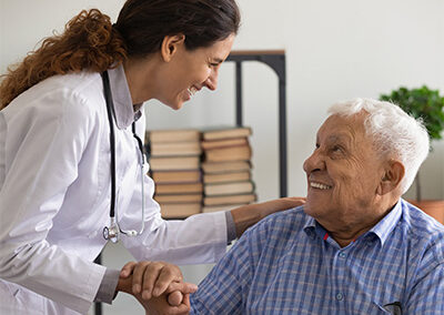 A doctor holding the hand of a senior in a wheelchair.