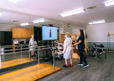 An elderly woman doing physical therapy in front of a TV at Valley Palms