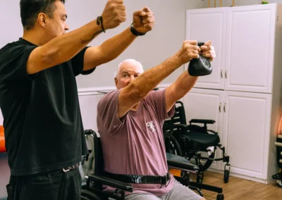 Am elderly man lifting a weight with a therapist at Casitas Care Center