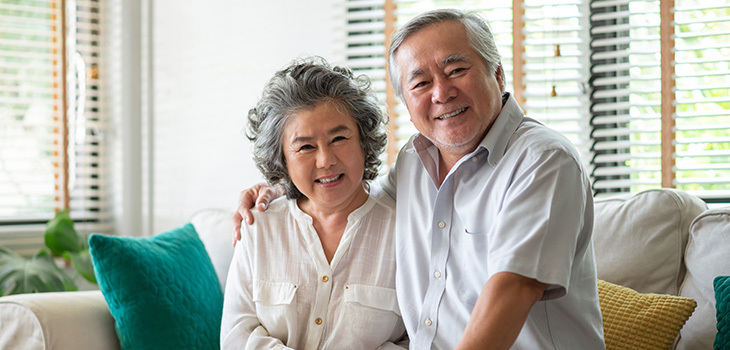 Two seniors embracing each other and smiling.