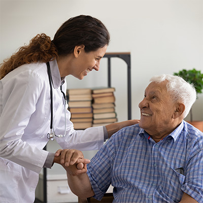 A doctor holding the hand of a senior in a wheelchair.