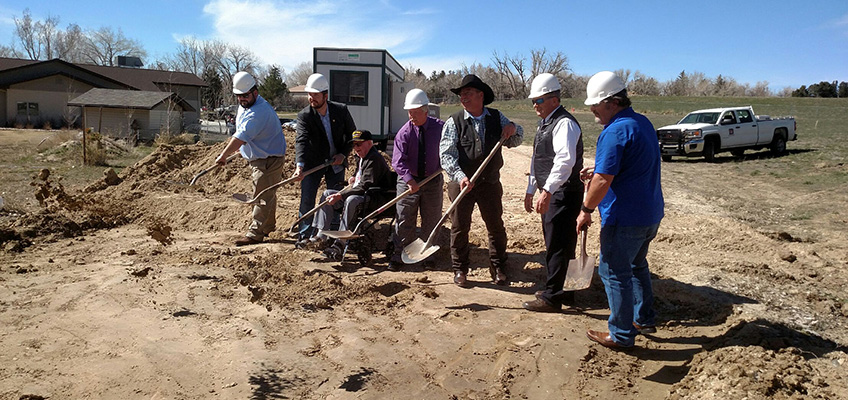 Ground breaking day with staff members digging in the dirt with hard hats on