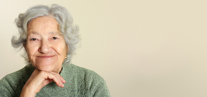 A senior smiling with her hand under her chin.