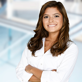 A young woman standing with her arms folded, smiling.