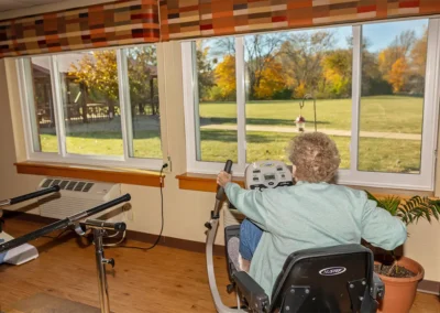 Senior using the rehabilitation bike overlooking the view outside the Farmington Village Nursing and Rehabilitation Center