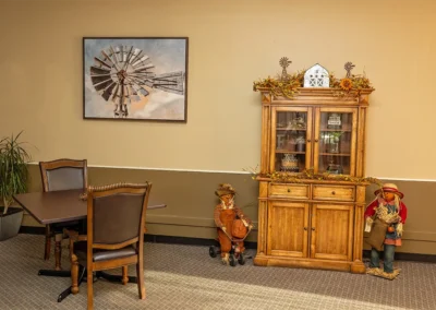 Communal space with tables, chairs, storage, and painting at the Farmington Village Nursing and Rehabilitation Center
