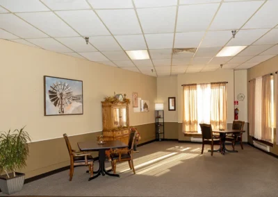 Communal space with tables, chairs, storage, and painting at the Farmington Village Nursing and Rehabilitation Center