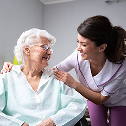 A nurse and a patient smiling at each other.