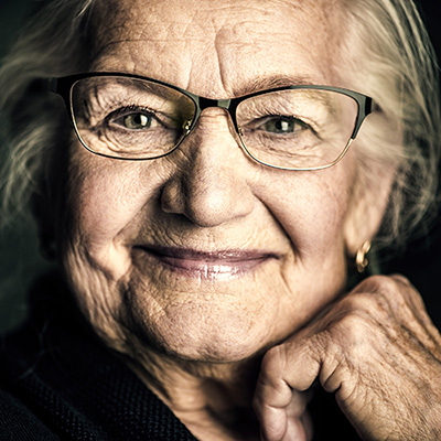 A senior woman smiling with her hand under her chin.