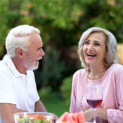 A senior couple dining outside and laughing together.