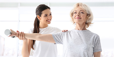 physical therapist with a resident in the rehab gym